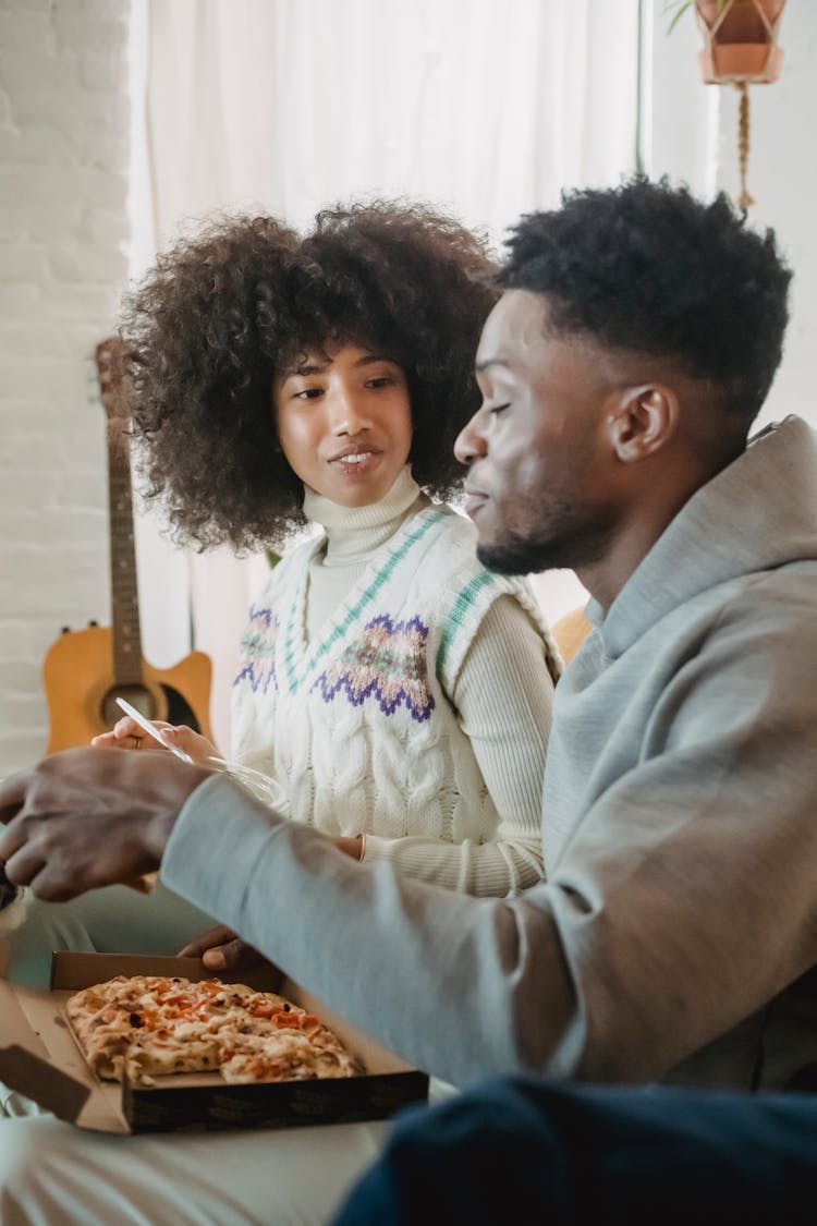 Beloved Young Black Couple Eating Appetizing Pizza Sitting Together On Couch