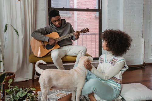 Free Black man playing guitar for girlfriend and dog Stock Photo