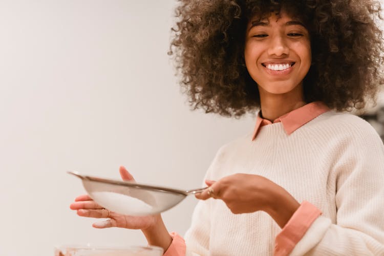 Cheerful Black Woman Sifting Flour