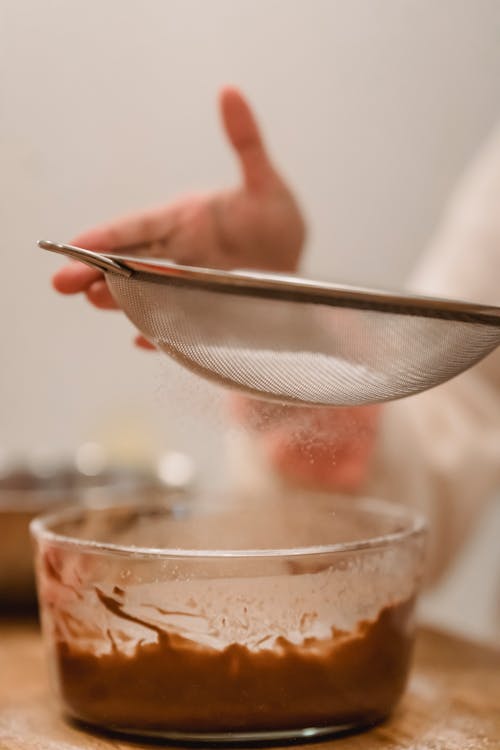 Crop chef pouring flour into bowl