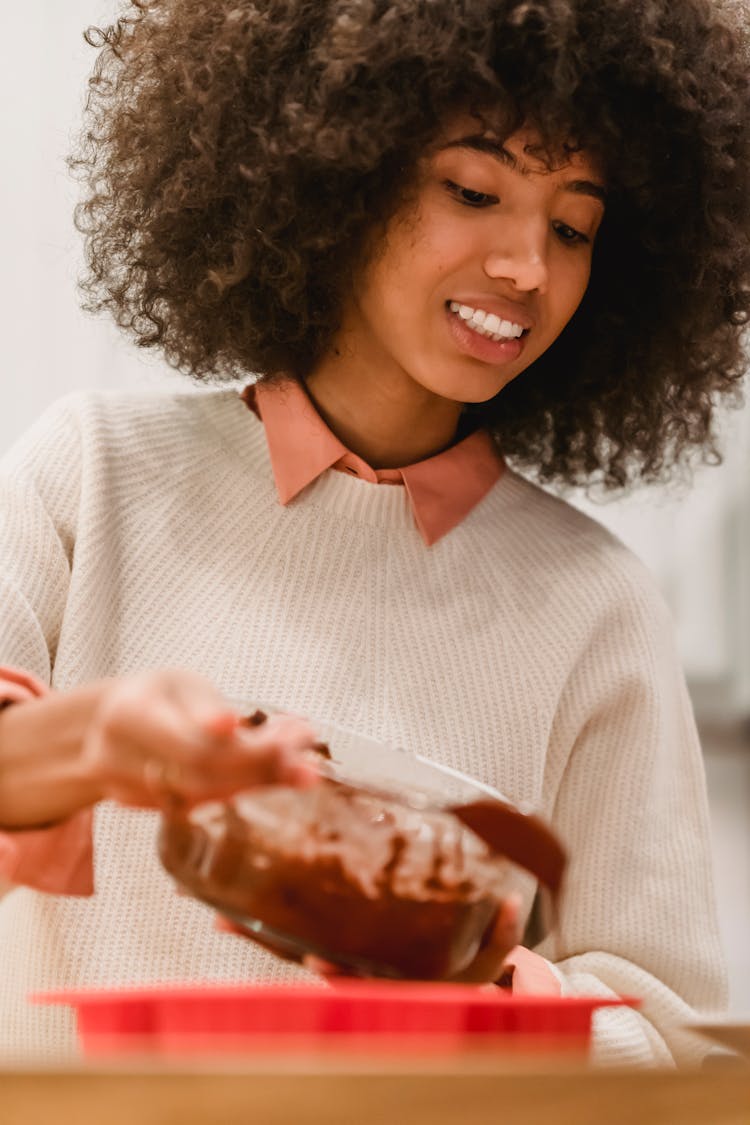 Smiling Black Woman Filling Molds With Batter