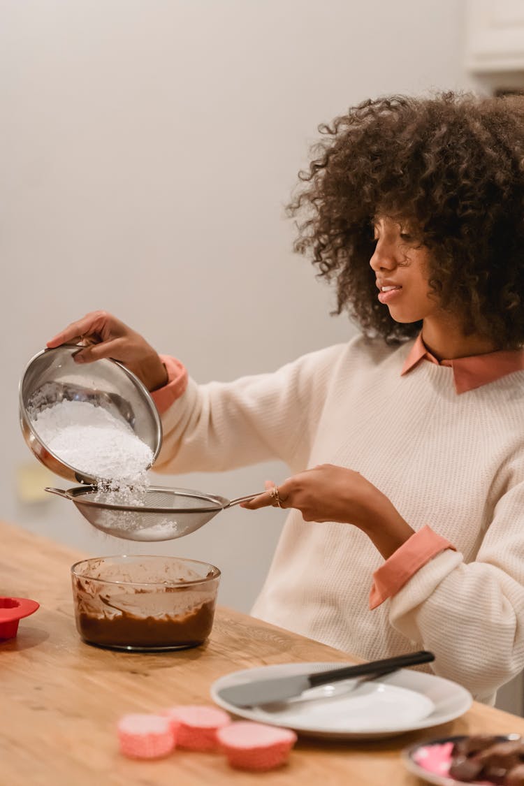 Concentrated Black Woman Adding Flour Into Strainer