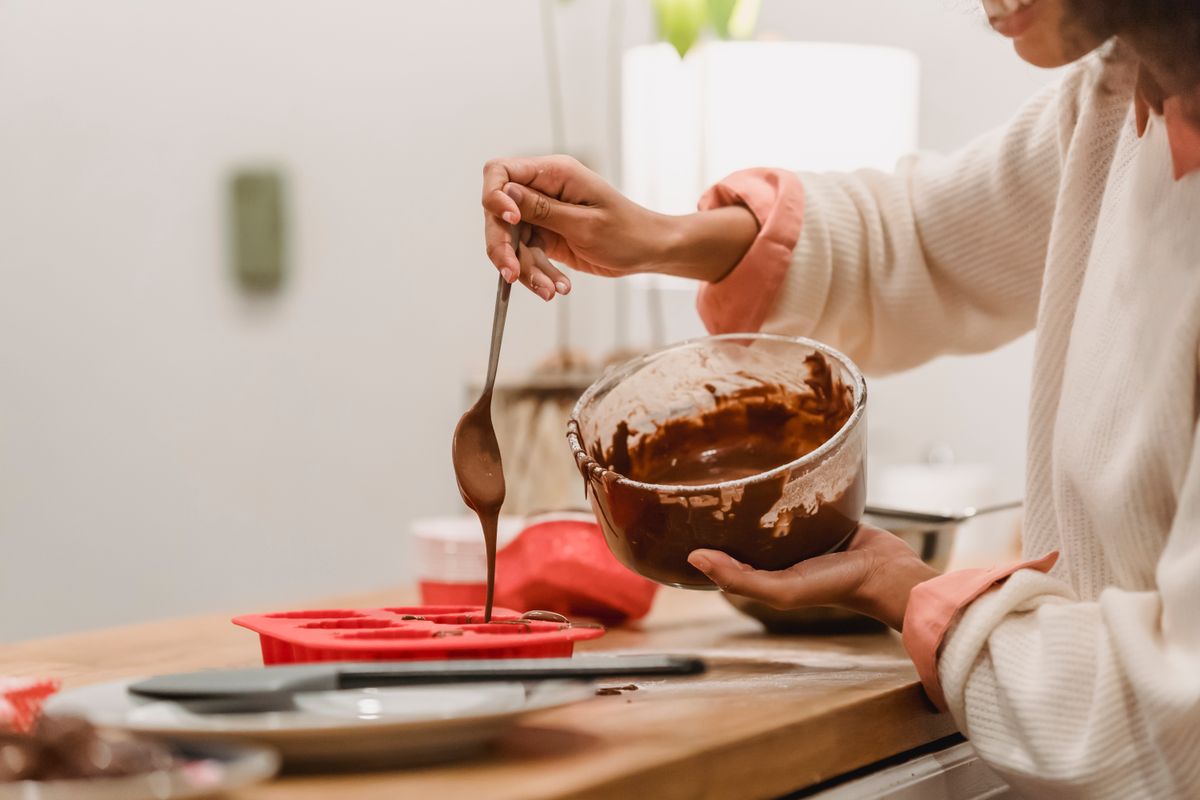 Chocolate batter being poured into a red silicone mold during food preparation
