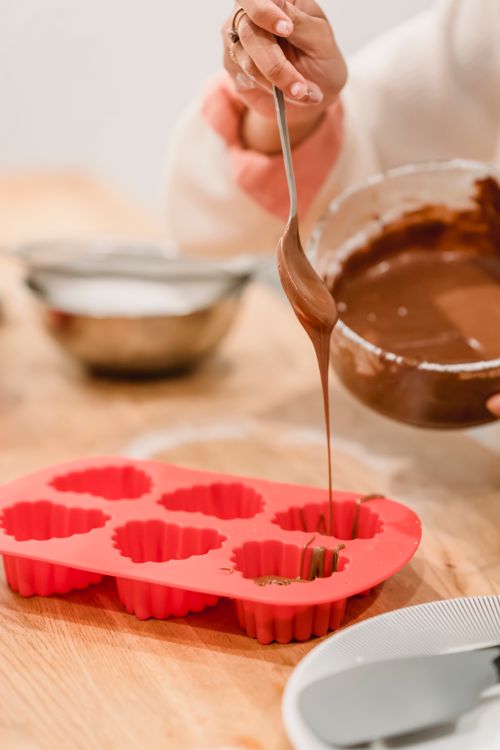 Free Crop anonymous African American female adding sweet delicious melted chocolate in red heart shaped silicone baking dish Stock Photo