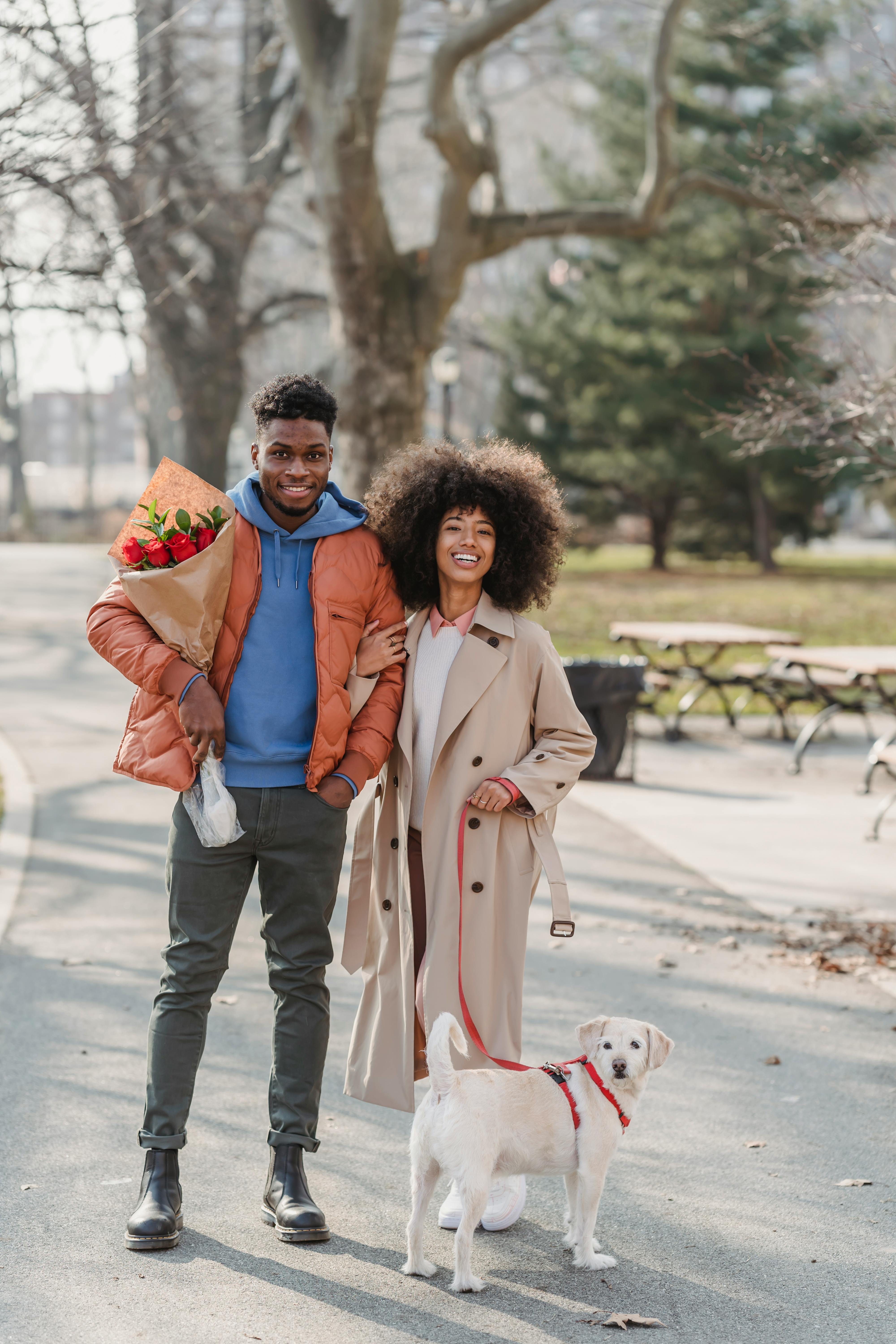 smiling african american couple standing with puppy in park