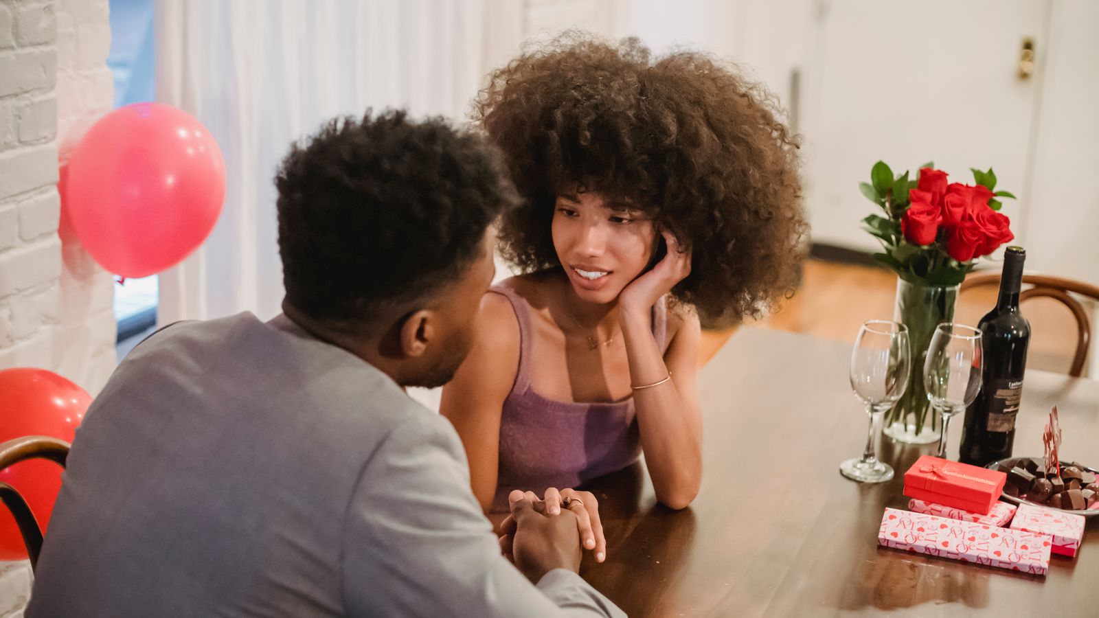 Two people holding hands and talking across a dinner table