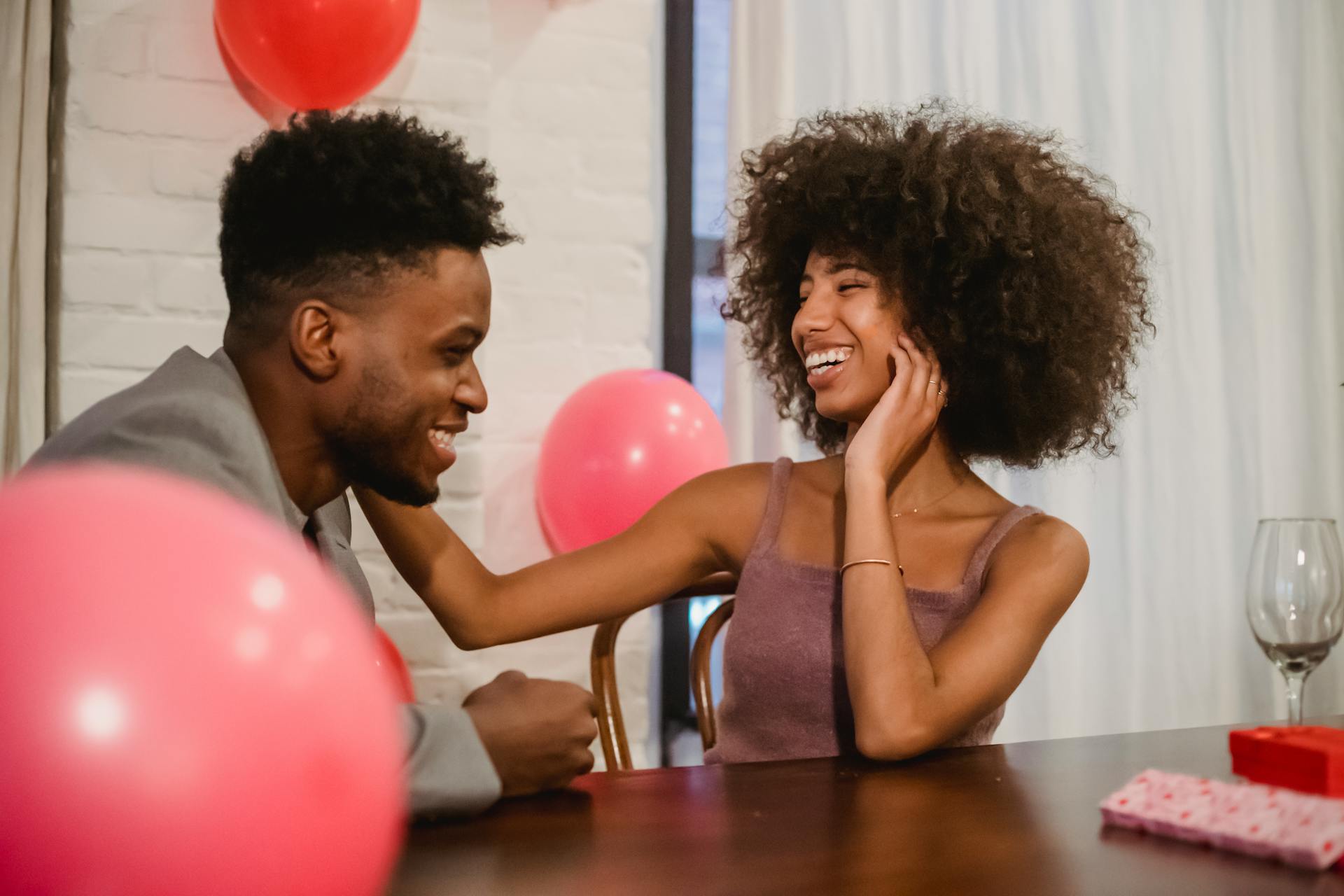 Happy couple enjoying a romantic indoor date with balloons, sharing laughs and love.