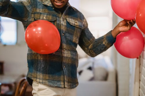 Free Anonymous ethnic guy decorating apartment with balloons Stock Photo