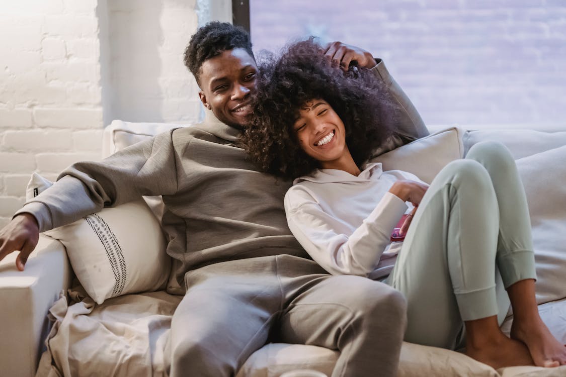 Beloved African American couple cuddling and smiling on couch