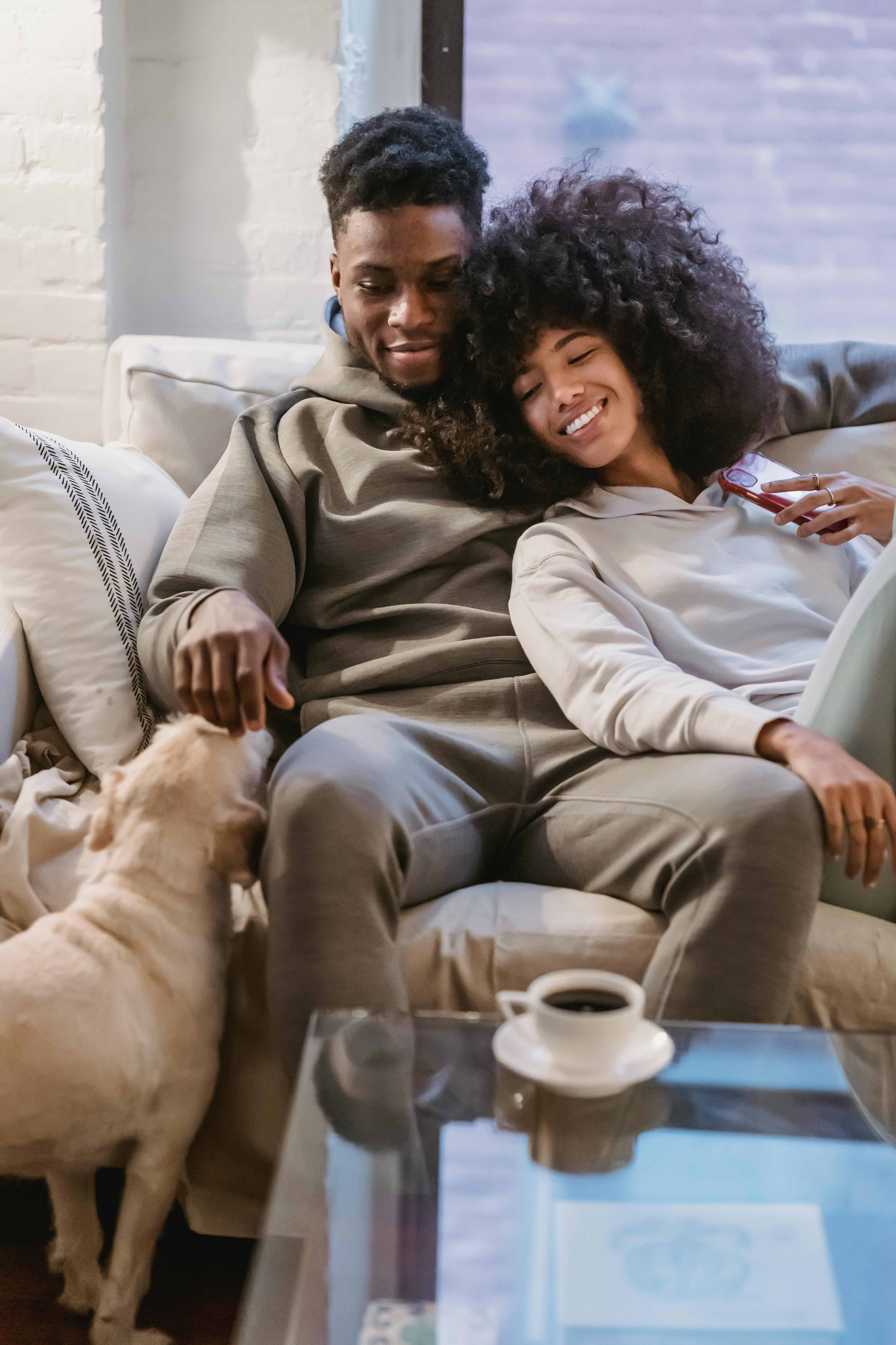 Young loving couple embracing on sofa and petting dog · Free Stock