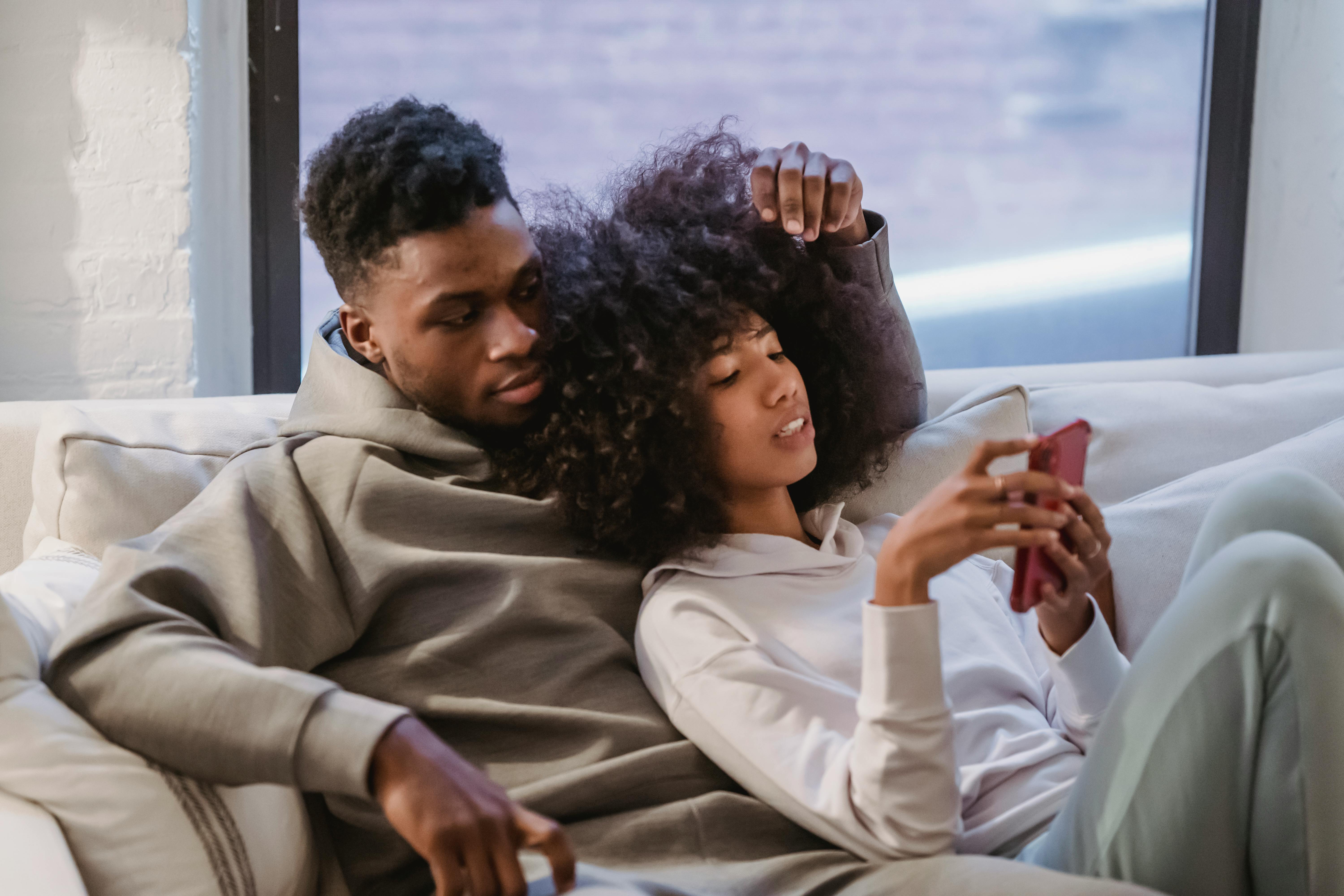 young black woman resting together with boyfriend and using smartphone