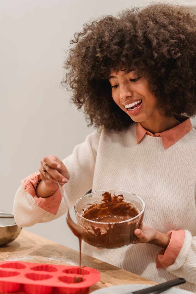 Cheerful Black Woman Filling Molds With Batter