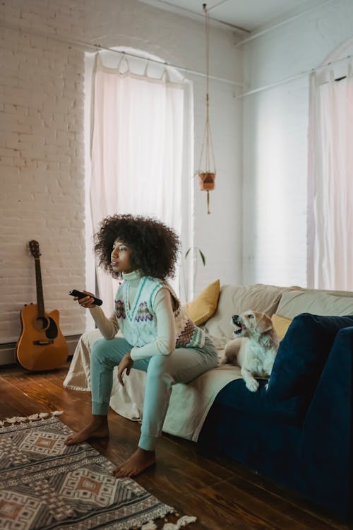 Black woman watching TV near dog