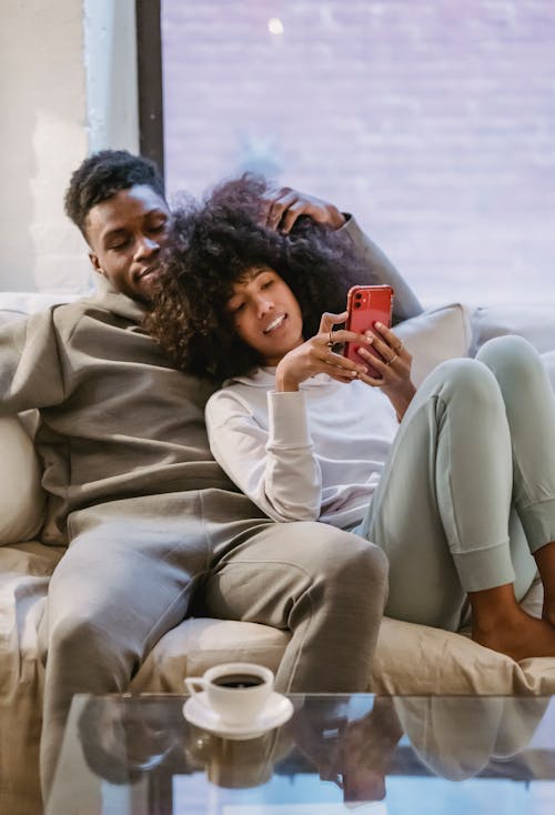 Free Content black couple browsing smartphone on couch Stock Photo