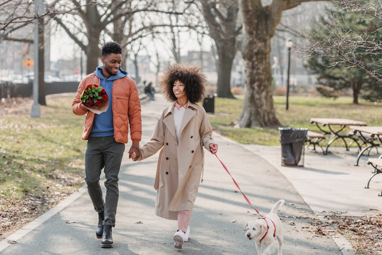 Positive Black Couple Walking In Park With Dog