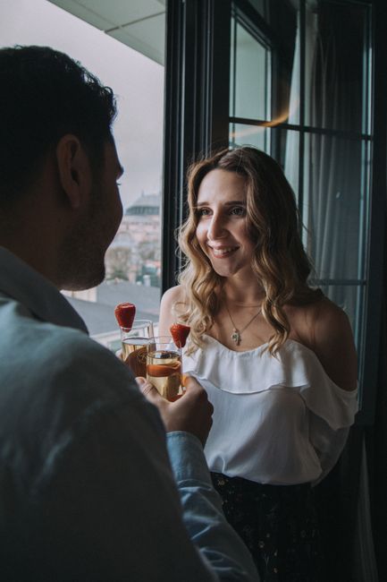 A young couple enjoying cocktails together in a romantic setting by a window.
