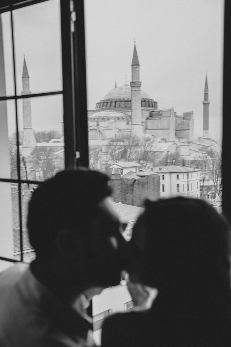 A Couple Kissing Near The Window