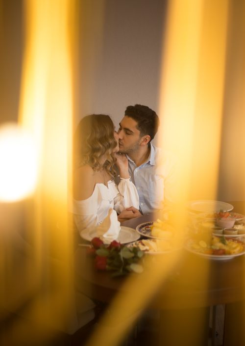 Free A romantic couple sharing a kiss during a cozy indoor dinner in Istanbul. Stock Photo