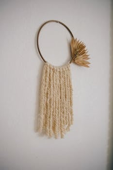 Decorative minimalist wall hanging with dried plants on a cream background.