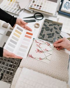 Top view of hands selecting color palettes and textile samples for interior design.