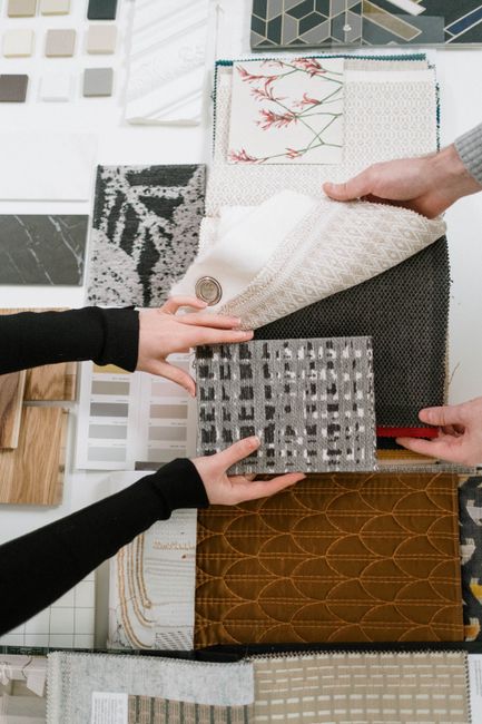 Hands selecting fabric samples for interior design projects.