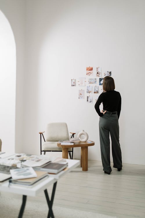 Free Woman in Black Long Sleeves and Gray Pants Looking at the Pictures on Wall  Stock Photo