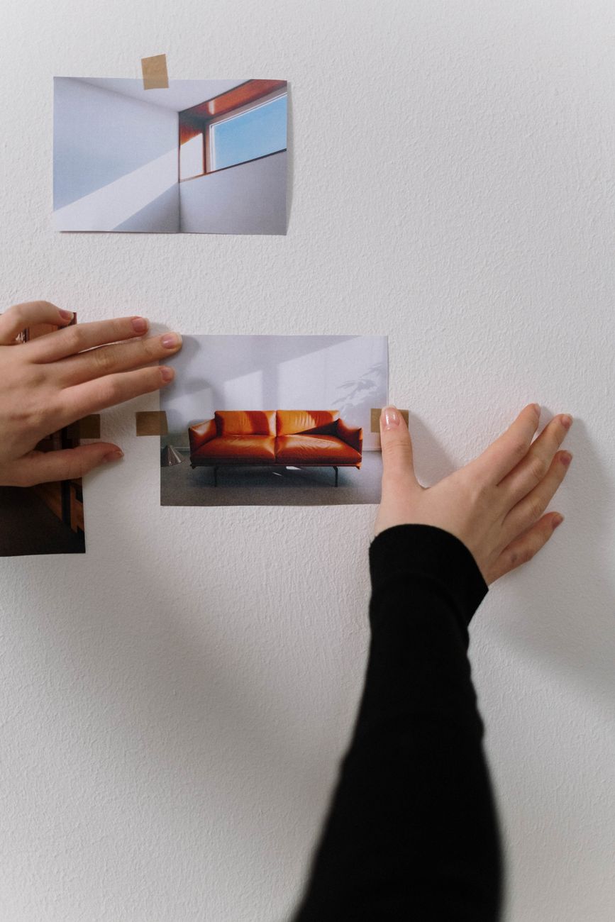 Hands placing photos on a wall to create a styling mood board