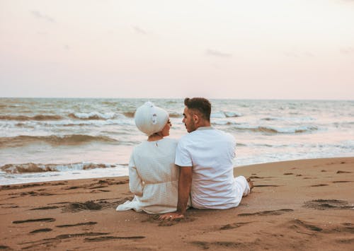 Free Backview of Couple sitting on a Beachside  Stock Photo