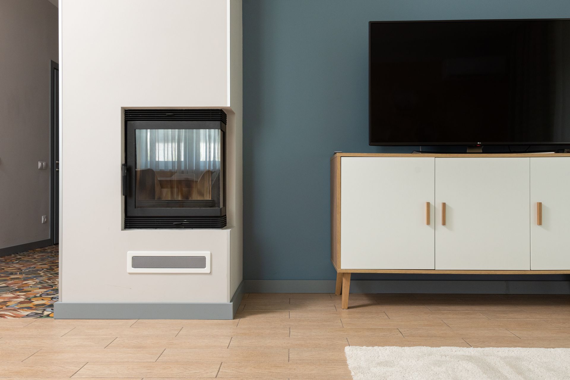 A contemporary living room featuring a minimalist fireplace and a large TV on a stylish cabinet.