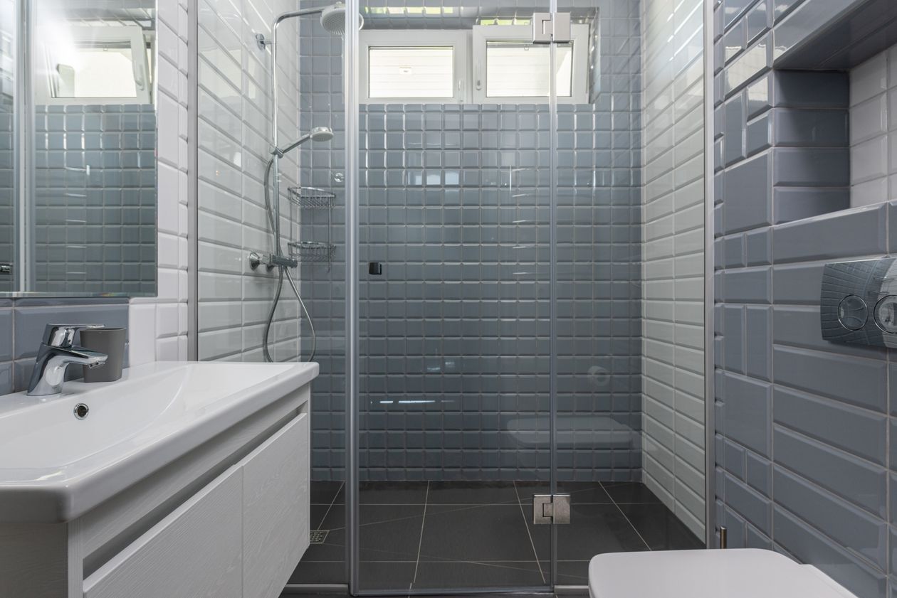 Glass shower enclosure with gray tile walls