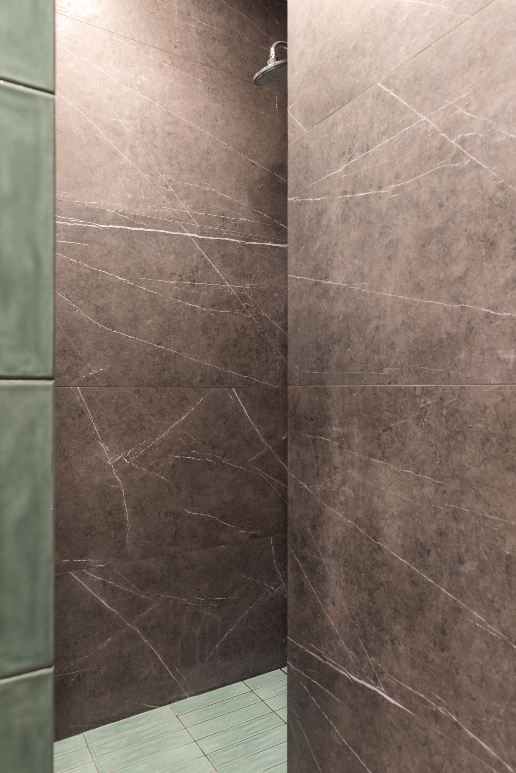 Green wet-zone finish beside marble surfaces and frequently cleaned shower details