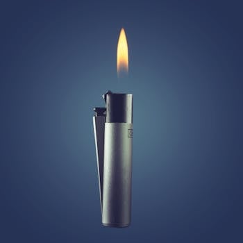 Close-up of a metallic lighter with a burning flame on a blue background. Minimalist design.