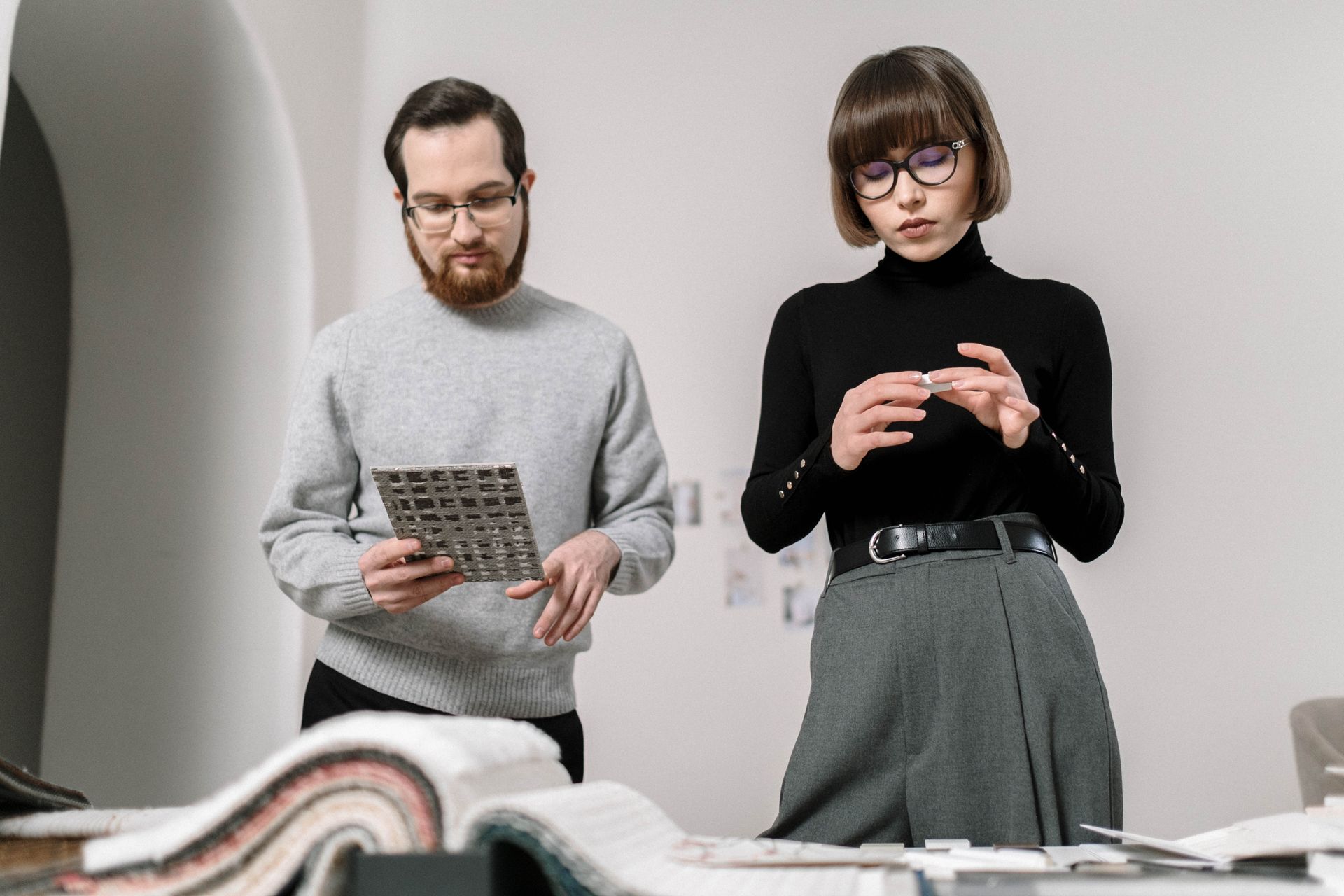 Two professionals discussing design samples in a modern office setting.
