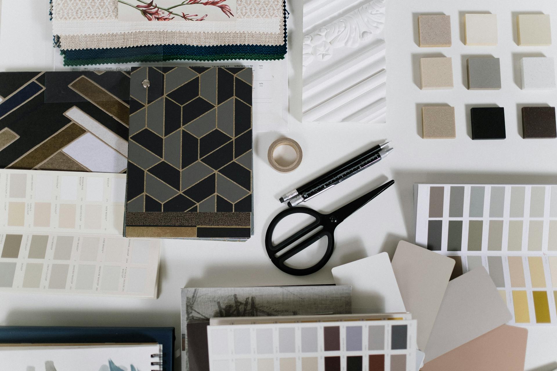 A neatly arranged flat lay of design tools and material samples for interior decoration inspiration.