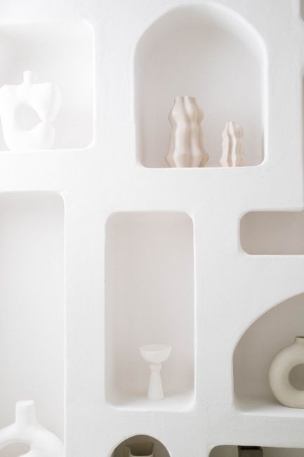 Calming white shelves displaying minimalist ceramic vases in modern interior.