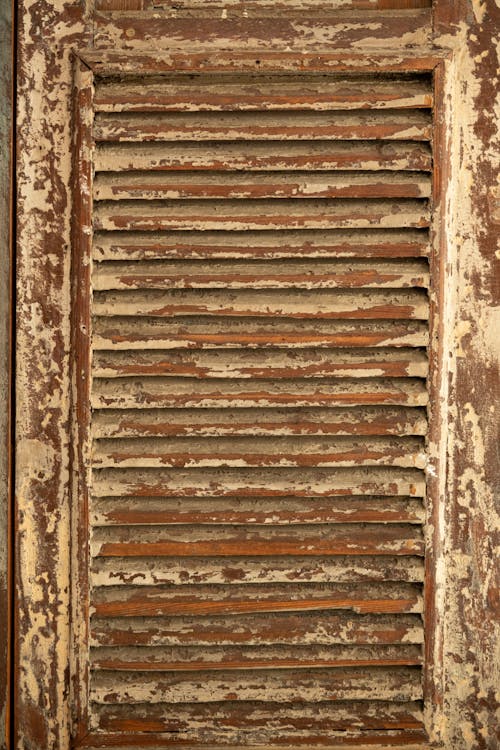 Textured backdrop of aged wooden shutter with blots on rough uneven brown surface in daytime