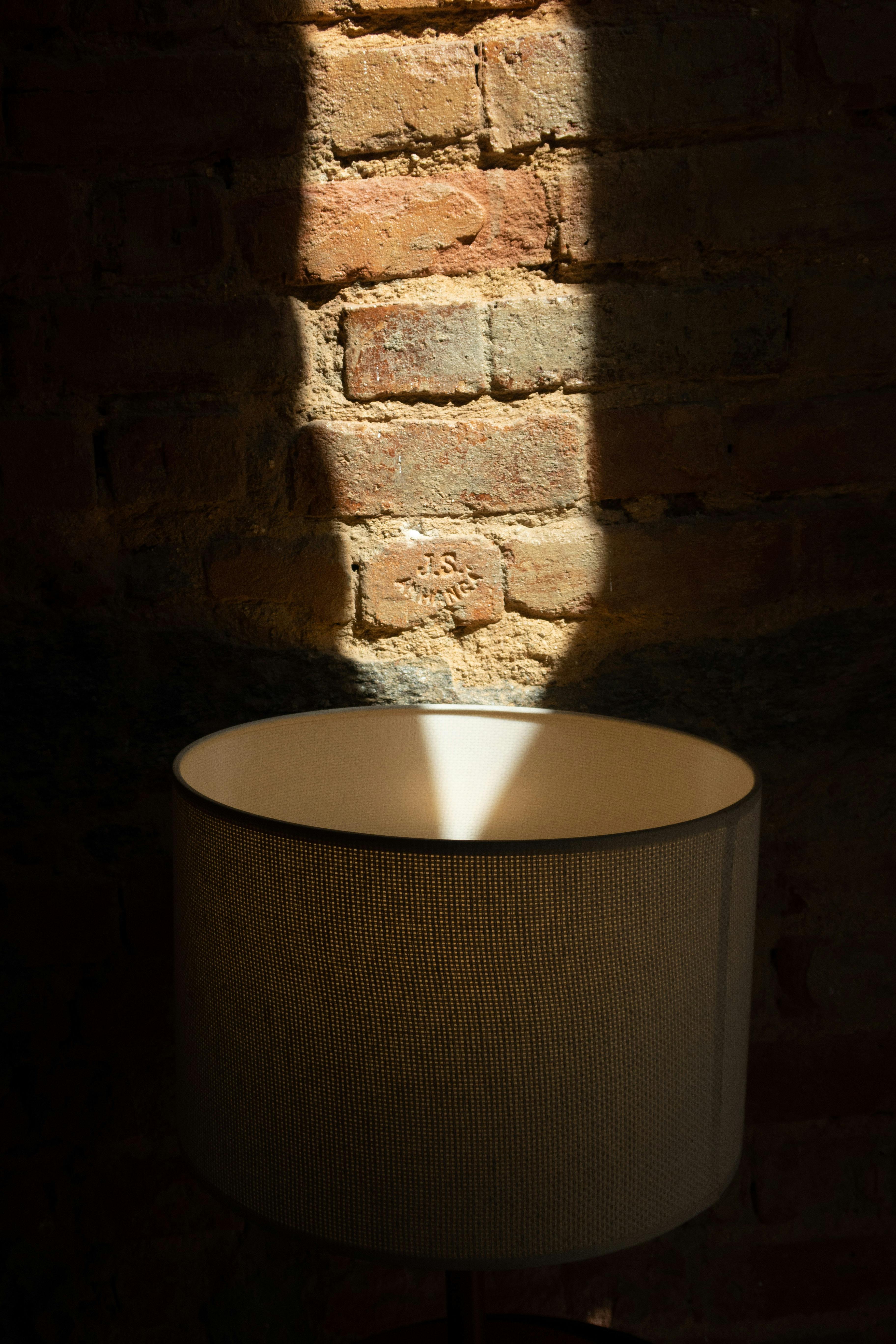Round shaped lamp near dry uneven wall with shades and cement on sunny day