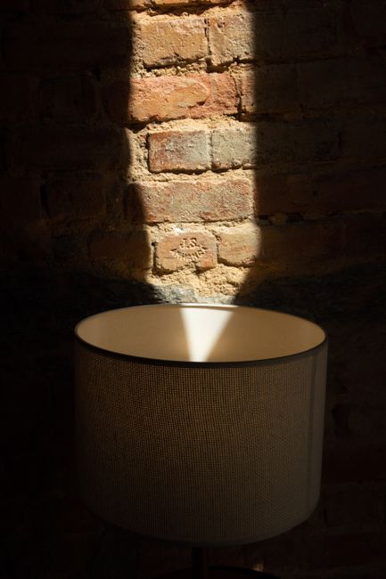 Round shaped lamp near dry uneven wall with shades and cement on sunny day