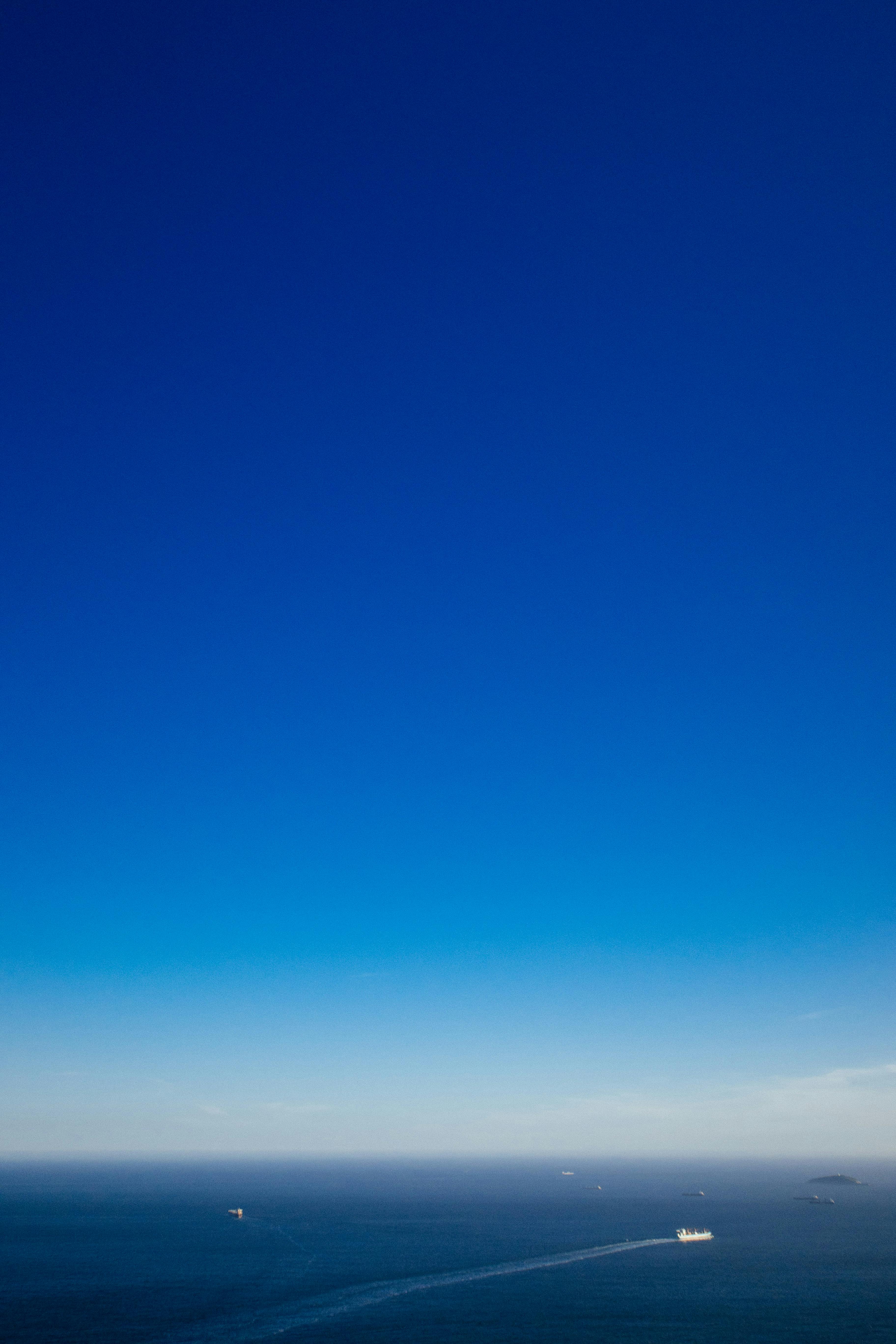 Aerial view of ships sailing on endless ocean under colorful blue sky with clouds in daytime