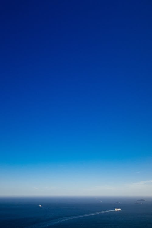 Ships sailing on sea under blue sky