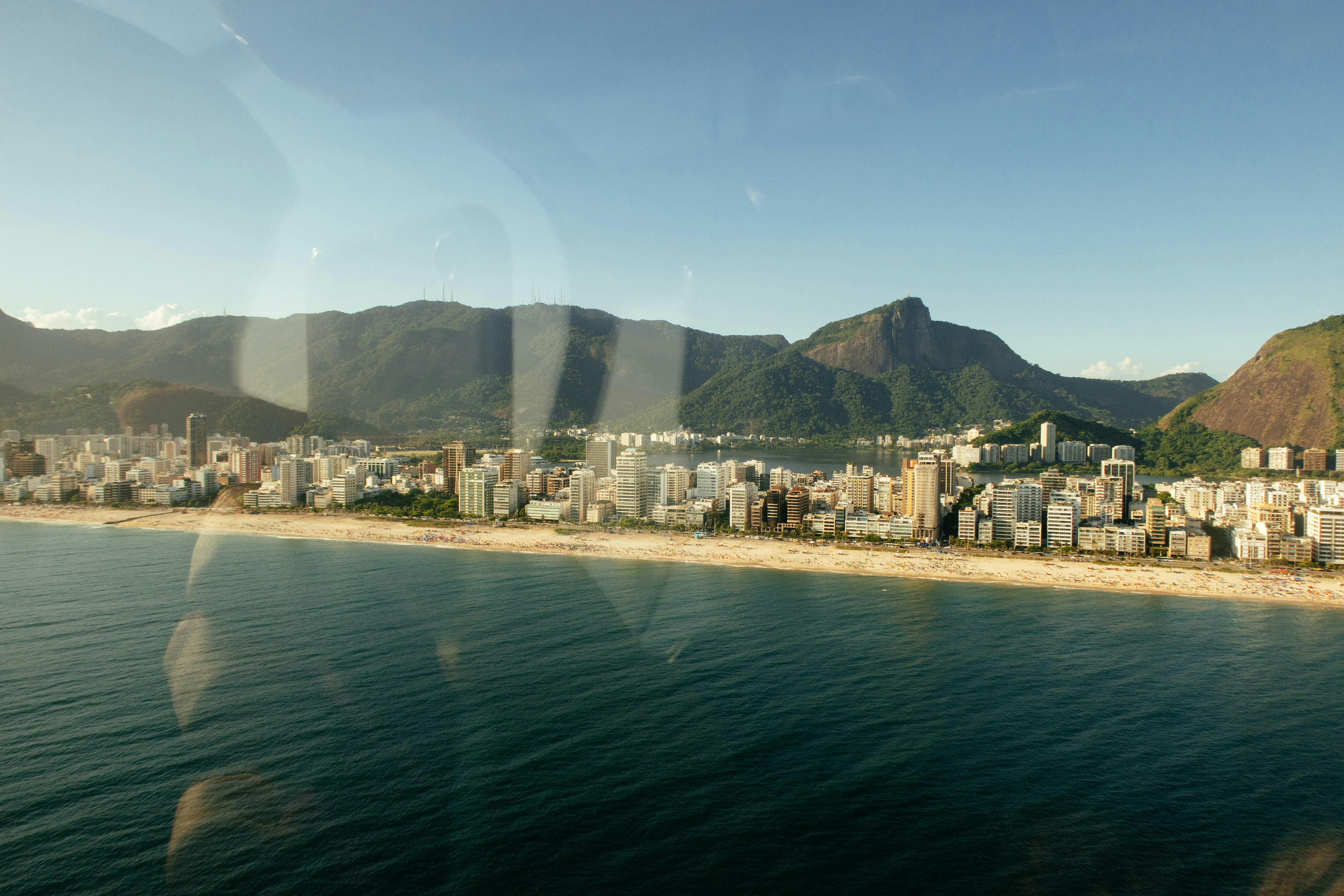 Beautiful aerial view of Rio de Janeiro's coastline with mountains and cityscape under a clear blue sky.