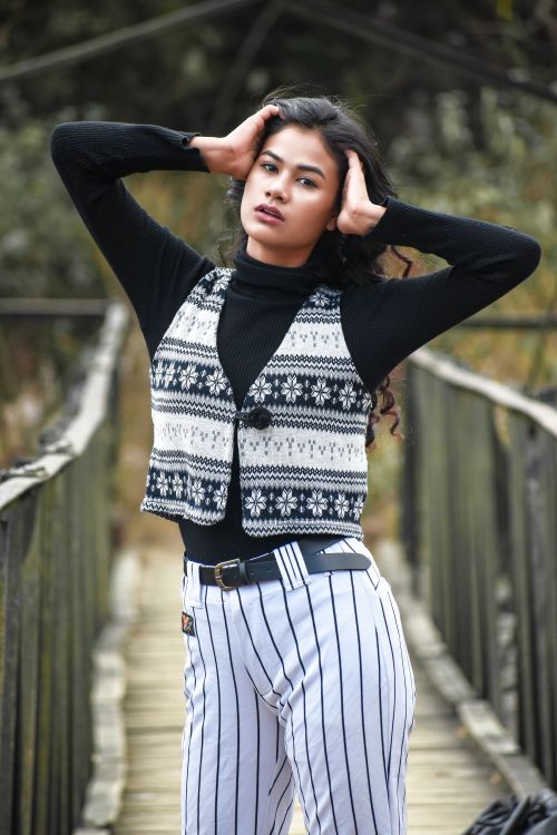 Free Fashionable young woman posing on a rustic bridge in stylish attire, embracing a modern look. Stock Photo