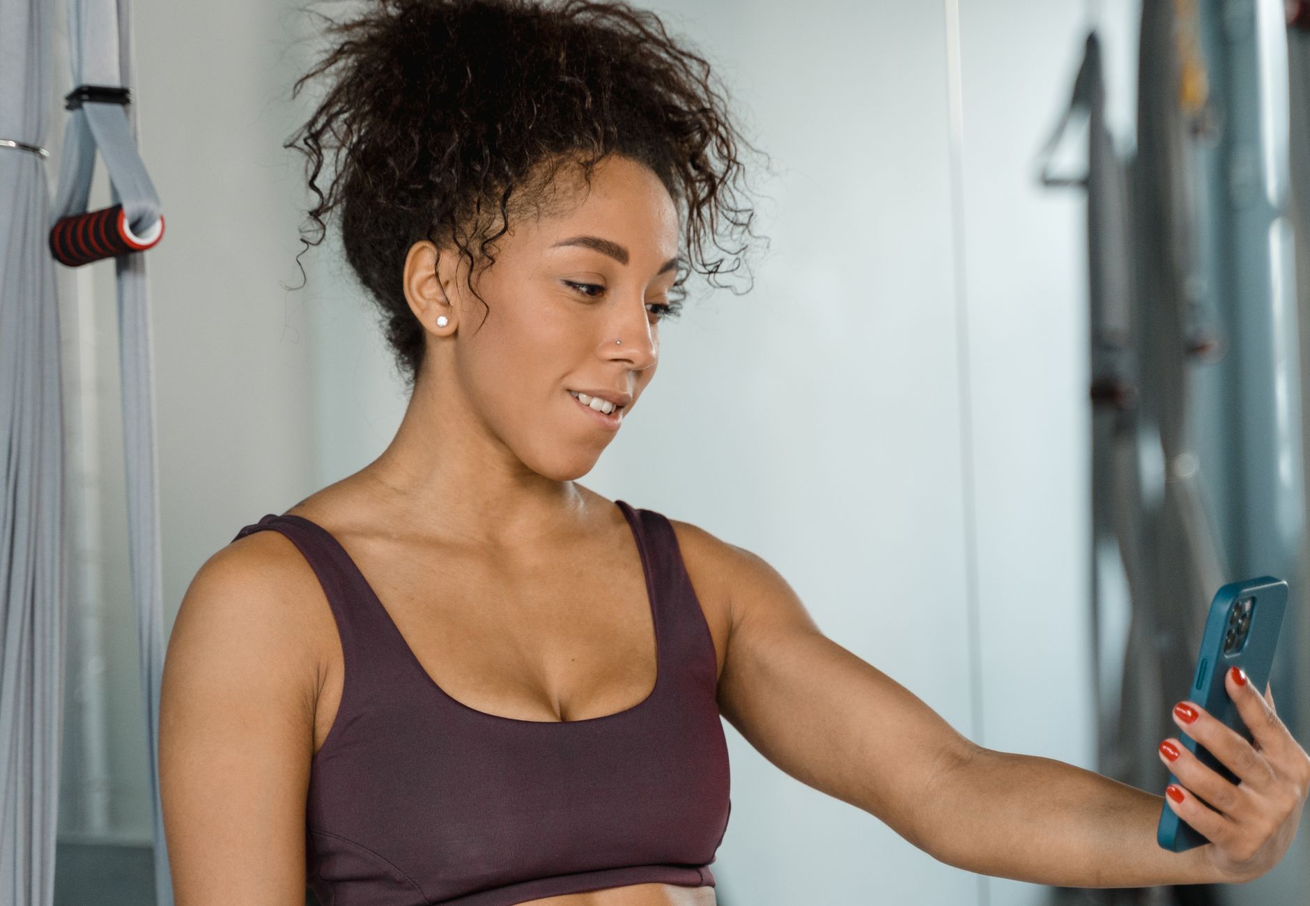 Woman in activewear using smartphone indoors at gym. Perfect for fitness and lifestyle themes.