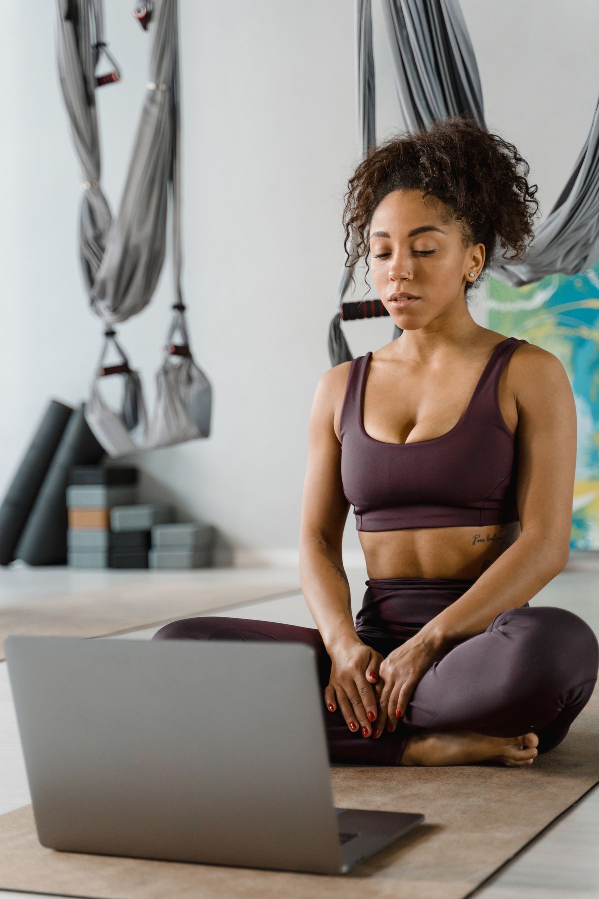 Woman seated by a laptop preparing for online yoga