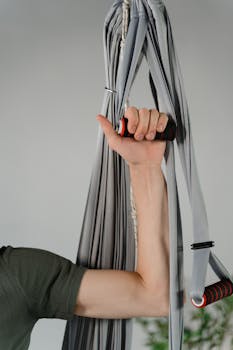 A person's hand grasping an aerial yoga hammock, emphasizing strength and grip.