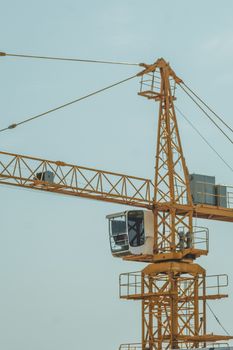 A yellow tower crane poised against a clear blue sky at a construction site, showcasing heavy machinery.