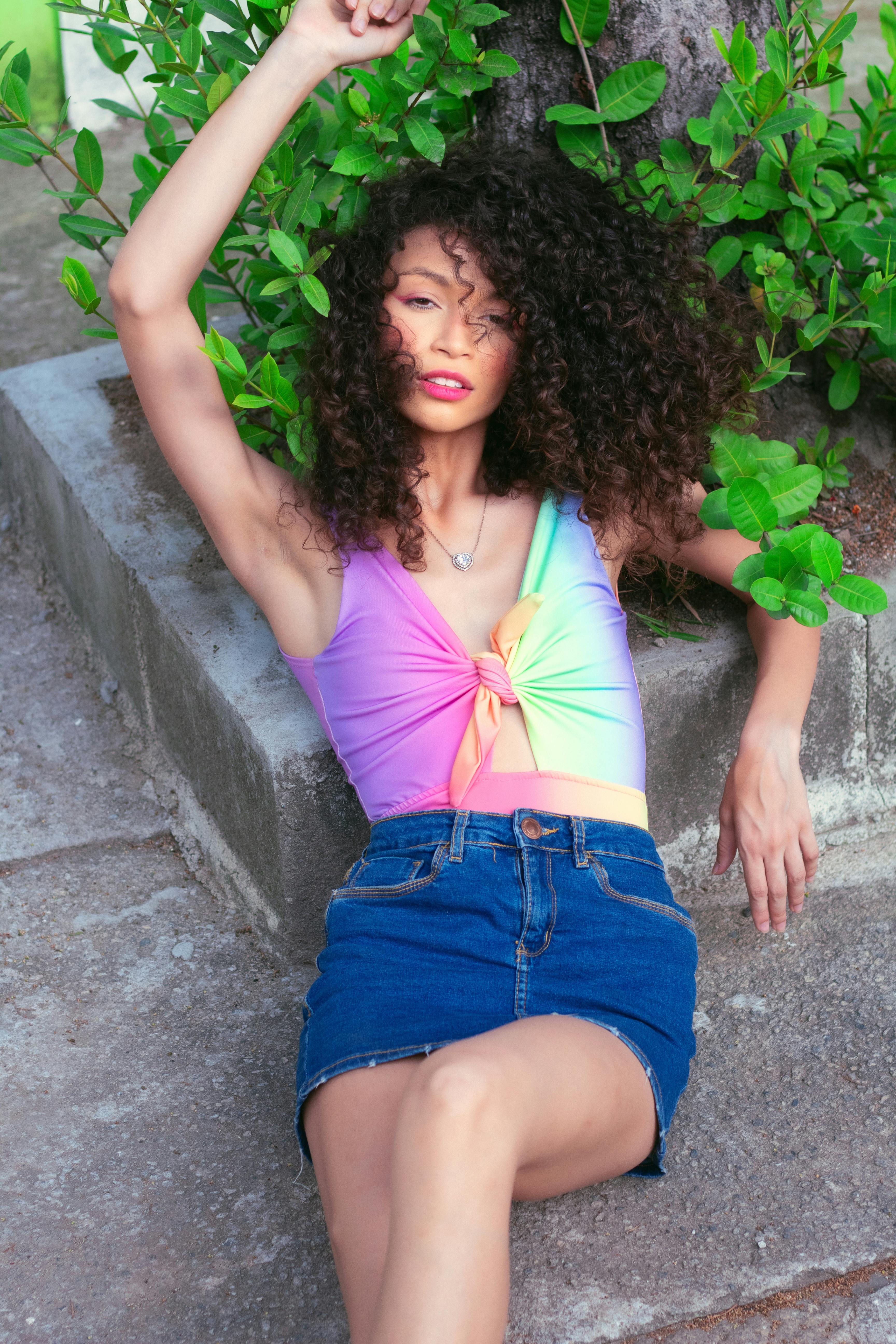 woman with curly hair lying near green leaves