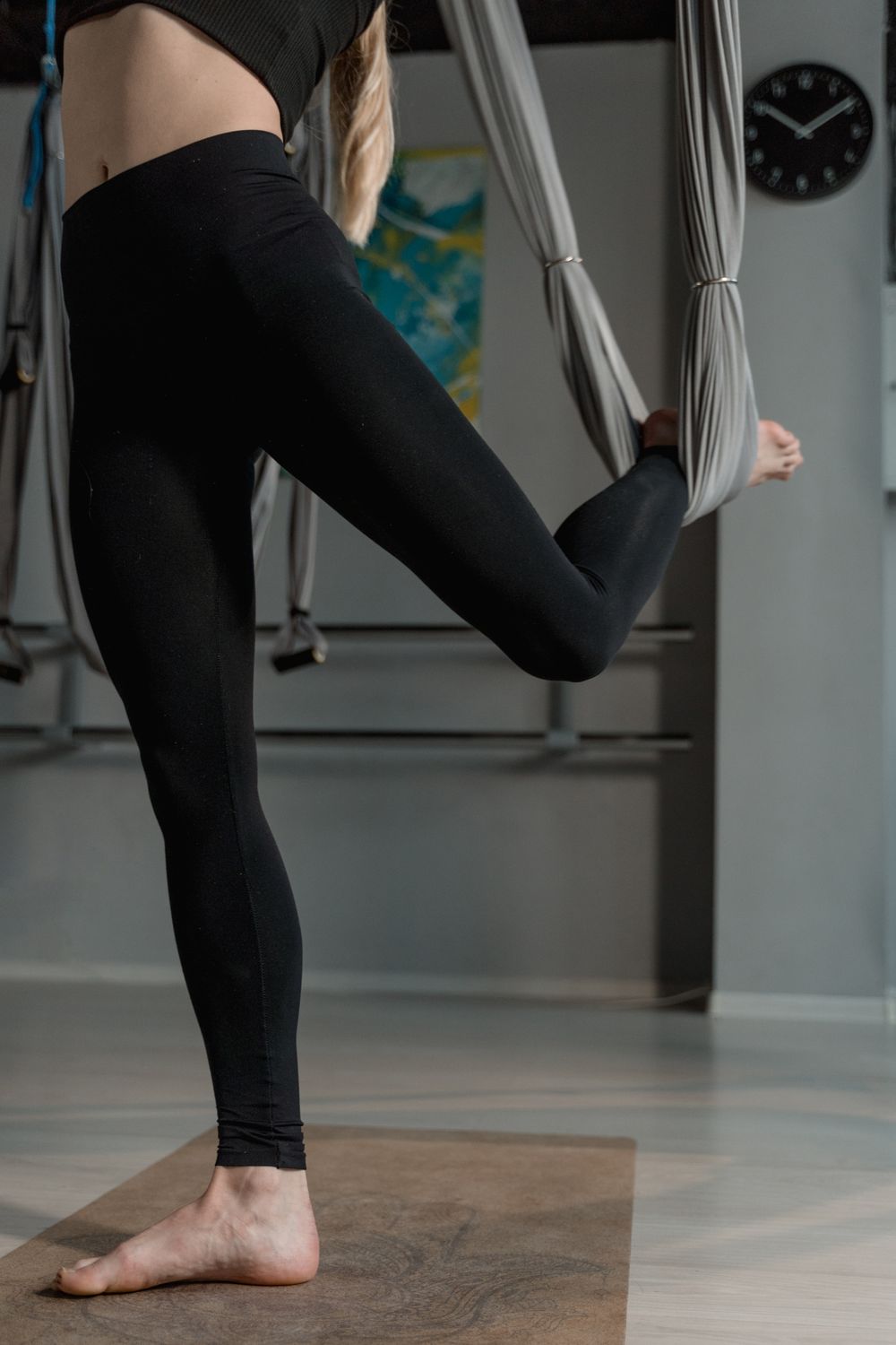 Hamak yoga için uzun tayt ve kapalı üst giymiş, kumaş hamakla çalışan kadın