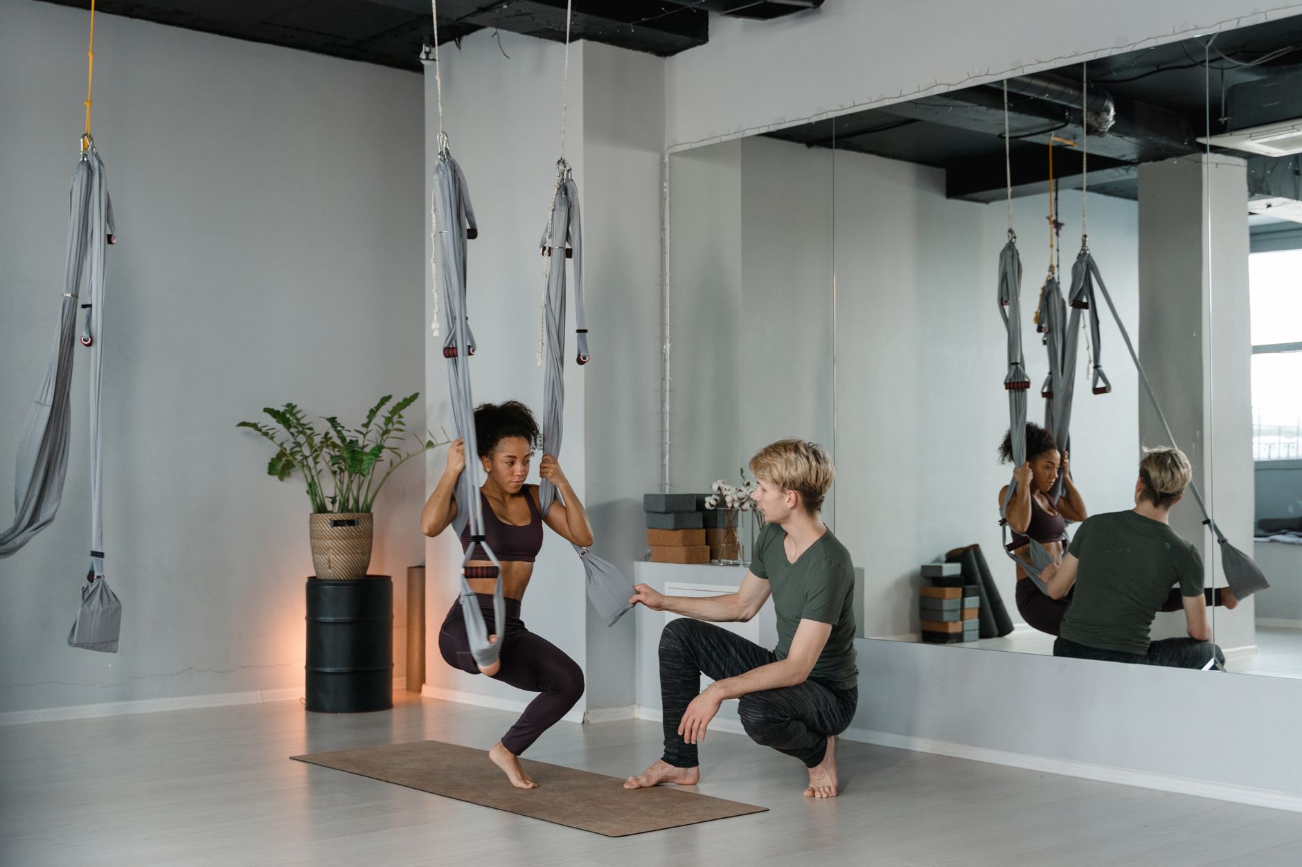 A Man Teaching Aerial Yoga to a Client