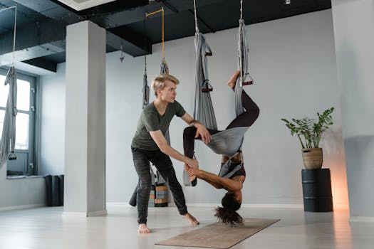 Aerial yoga session featuring an instructor assisting a student in a modern studio.